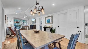 A dining area with a wooden table, chairs, and a hanging light fixture.