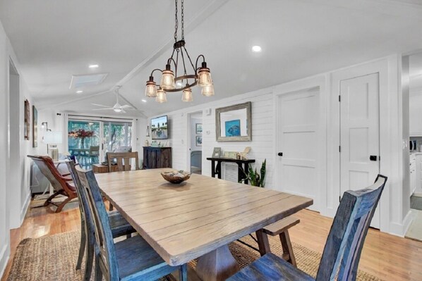 A dining area with a wooden table, chairs, and a hanging light fixture. - Award-Winning Resort Amenities | Twin Oaks 40 (Isle Of Palms)