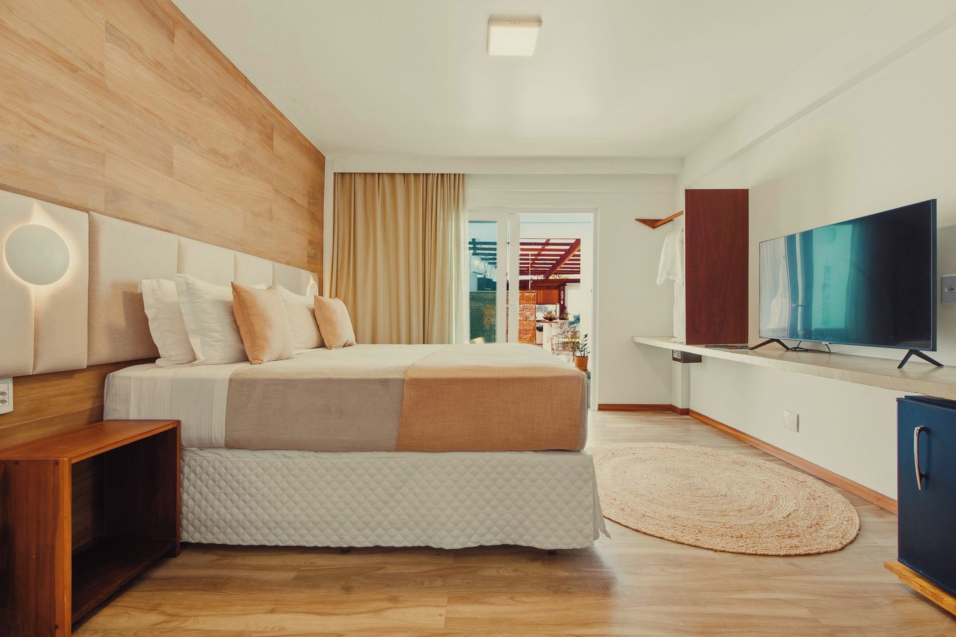 A modern bedroom with a bed, a TV, and a wooden floor.