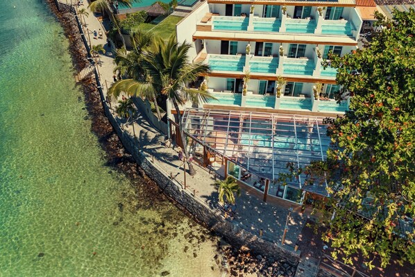 A beachfront hotel with multiple swimming pools, a sandy beach, and palm trees. - AQUA BY SAMBASS (Cairu)