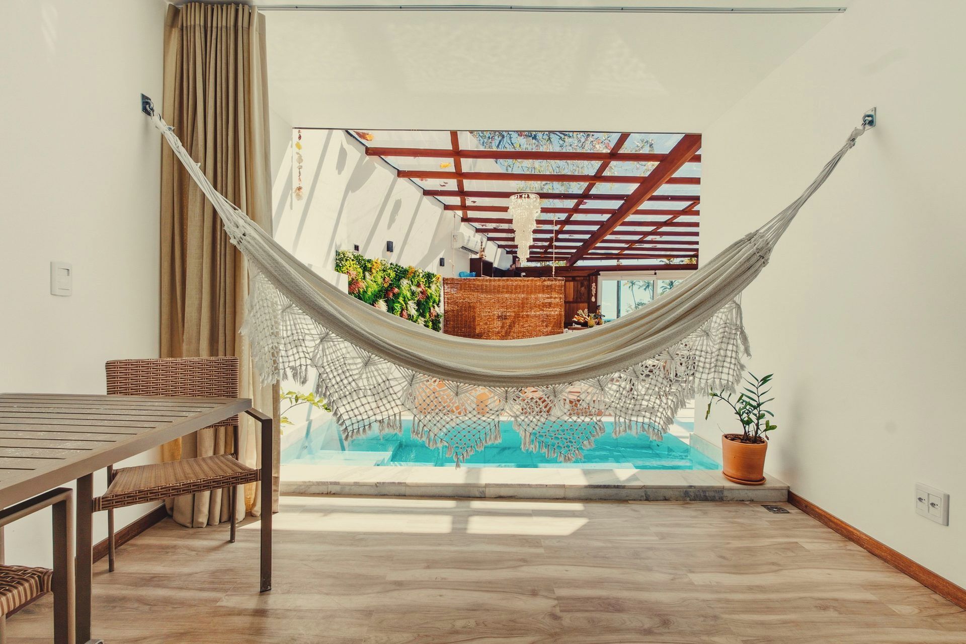 Eine Hängematte in einem Zimmer mit Blick auf einen Pool und einem Holztisch.