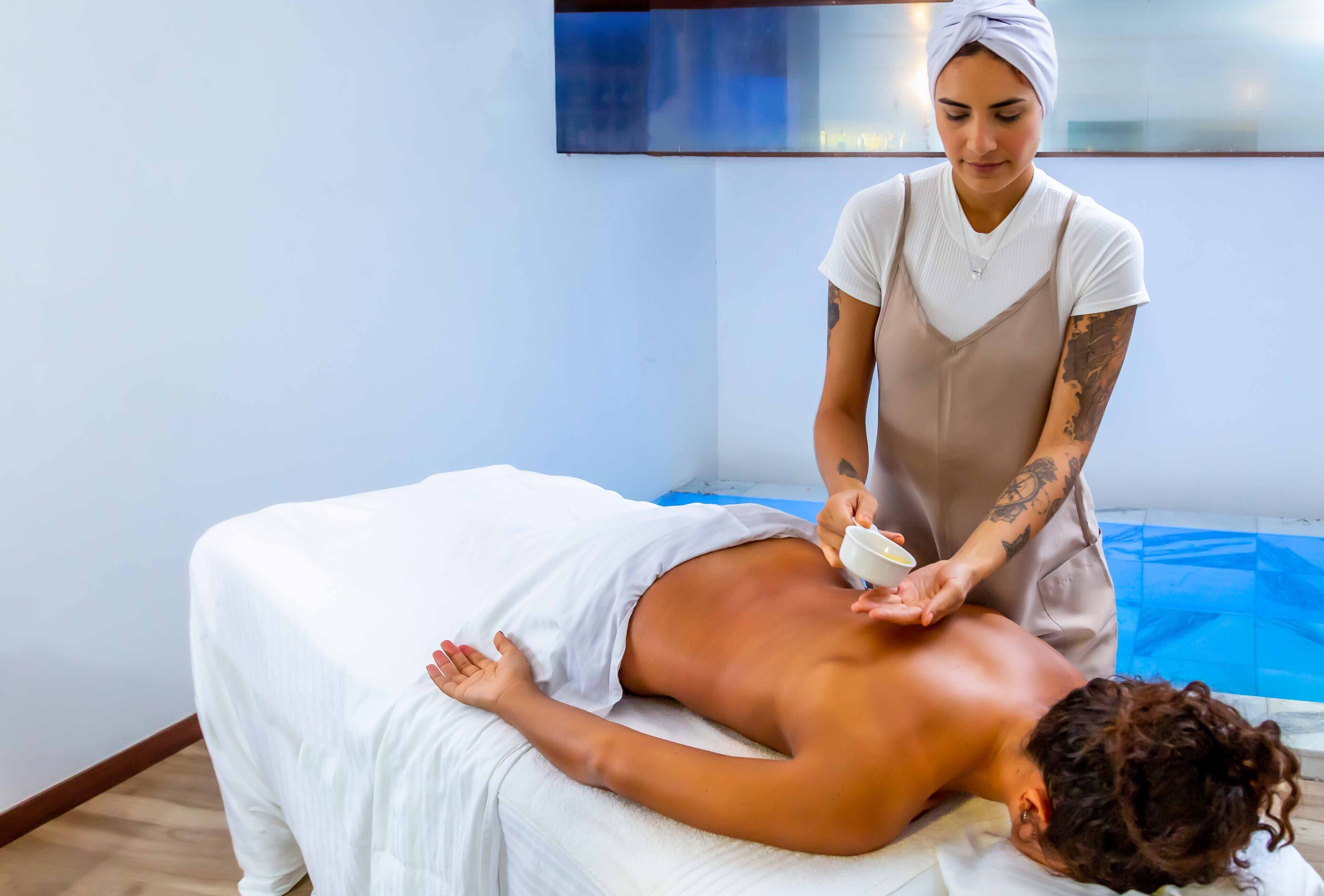 A massage therapy session in a room with a wooden floor and a blue mat.