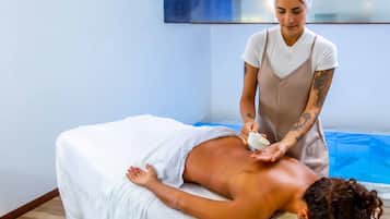 A massage therapy session in a room with a wooden floor and a blue mat.