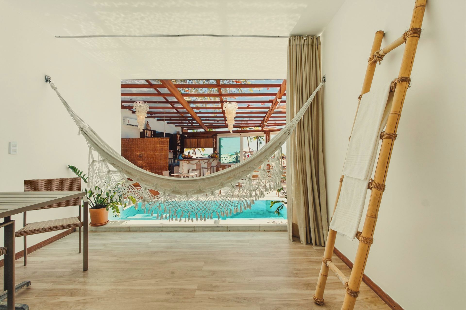 Ein Zimmer mit einer Hängematte, einem Pool und einer Bambusleiter.