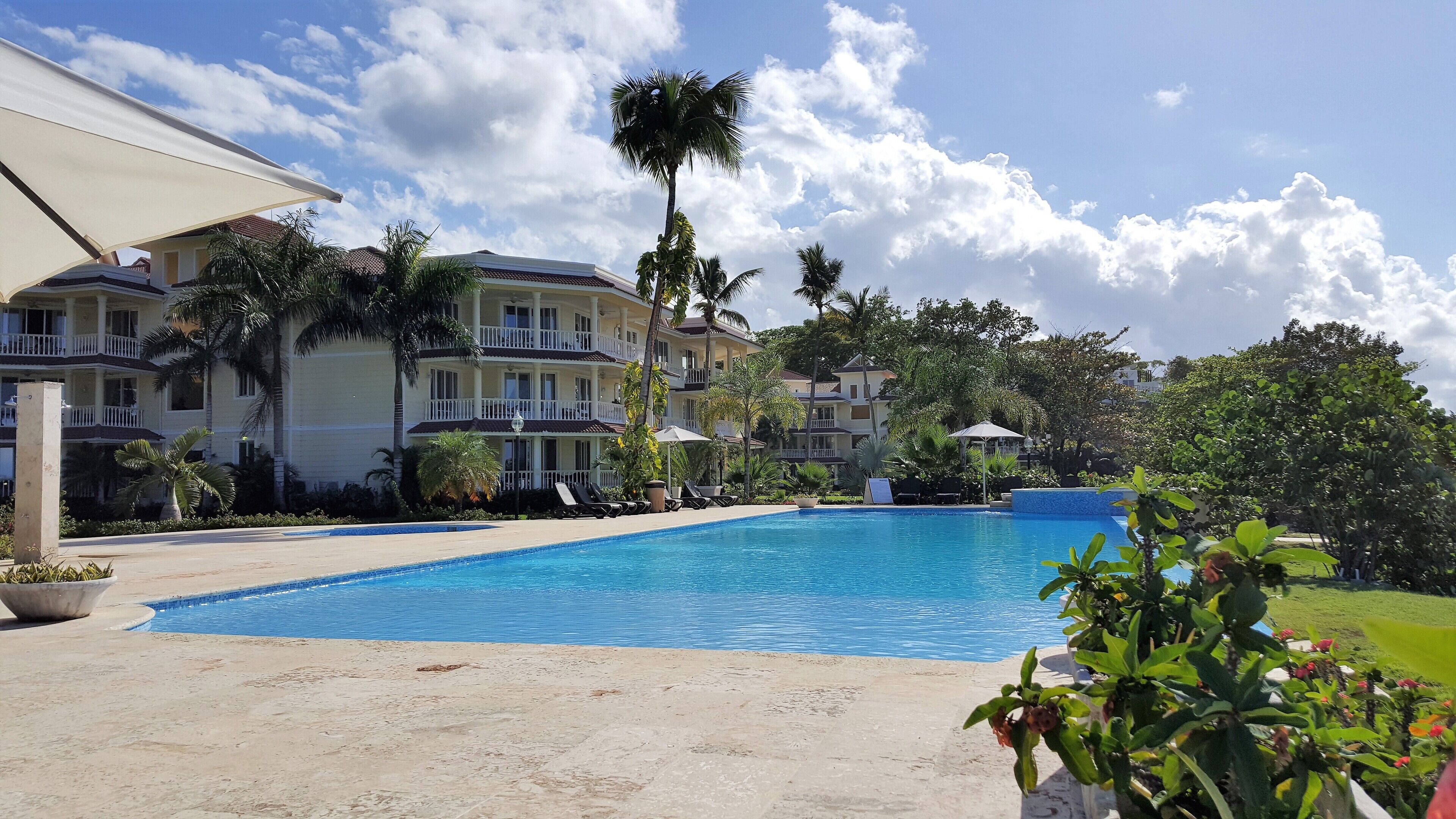 Ett hotell med en swimmingpool, palmer och en klar himmel.