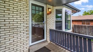 A brick exterior with a glass door and a small porch with a railing.