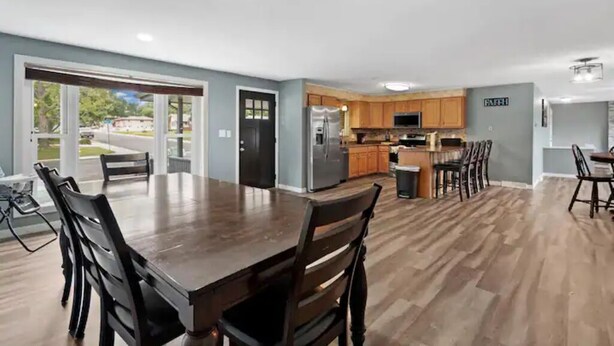 A spacious kitchen with wooden cabinets, a stainless steel refrigerator, and a dining area with a large wooden table and chairs.