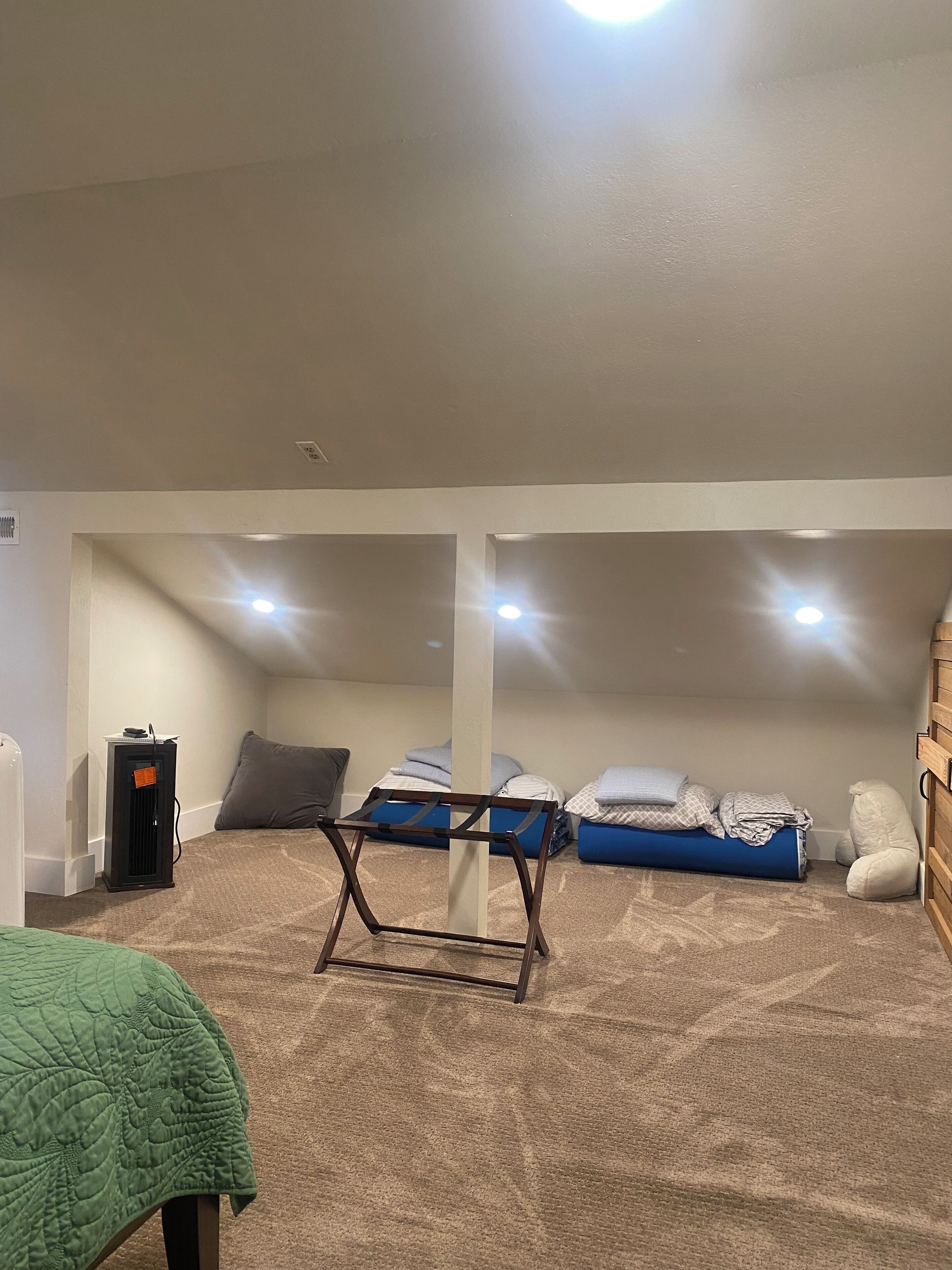 Una habitació amb dos llits superposats, un radiador portàtil i una manta verda sobre una cadira.