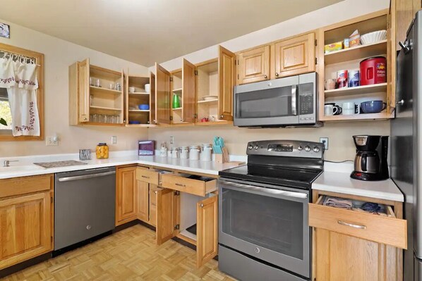 A modern kitchen with wooden cabinets, a stainless steel stove, a microwave, and a dishwasher.
