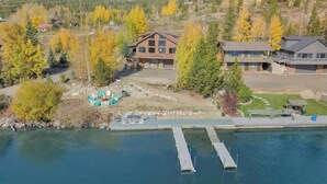 A lakeside property with a dock, a swimming area, and a building with a large deck.