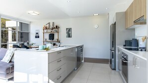 Una cocina moderna con armarios blancos, electrodomésticos de acero inoxidable y una isla central con un lavamanos.