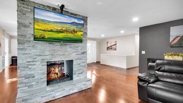 Uma sala de estar moderna com lareira de pedra, uma TV de tela plana montada e um sofá de couro.