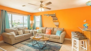 A living room with two sofas, a coffee table, and a staircase against an orange wall. - Cowboy Pool / Mini Golf / Walk 2 Beach & Ocean Center! Pets OK (Daytona Beach)