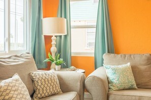 Ein Wohnzimmer mit zwei Sofas, einer Lampe, einem Blumentopf und einem Fenster mit Vorhängen.
