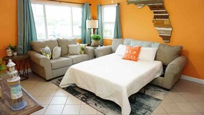 A living room with a sofa, a bed, a lamp, and a staircase. - Cowboy Pool / Mini Golf / Walk 2 Beach & Ocean Center! Pets OK (Daytona Beach)