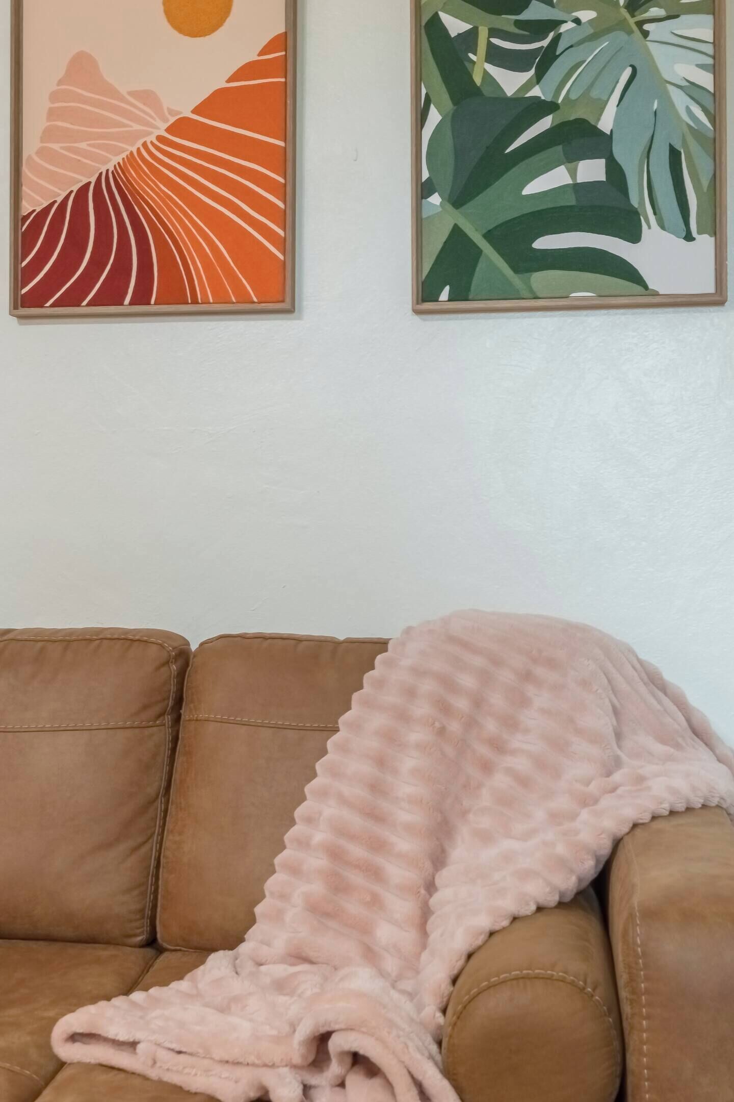 A brown leather sofa with a pink blanket.
