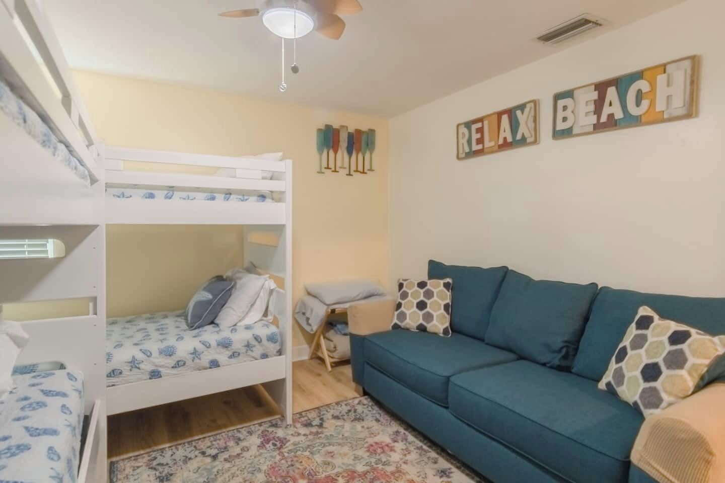 A room with bunk beds, a sofa, and a 'Relax Beach' sign.