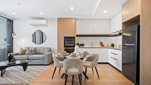 Een moderne keuken met een ingebouwde oven, een roestvrijstalen koelkast en een eethoek met een glazen tafel en stoelen.