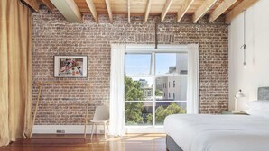 A bedroom with a brick wall, a large window, a bed, and a chair. - New York-Style Loft in Sydney CBD with City Views (Darlinghurst)