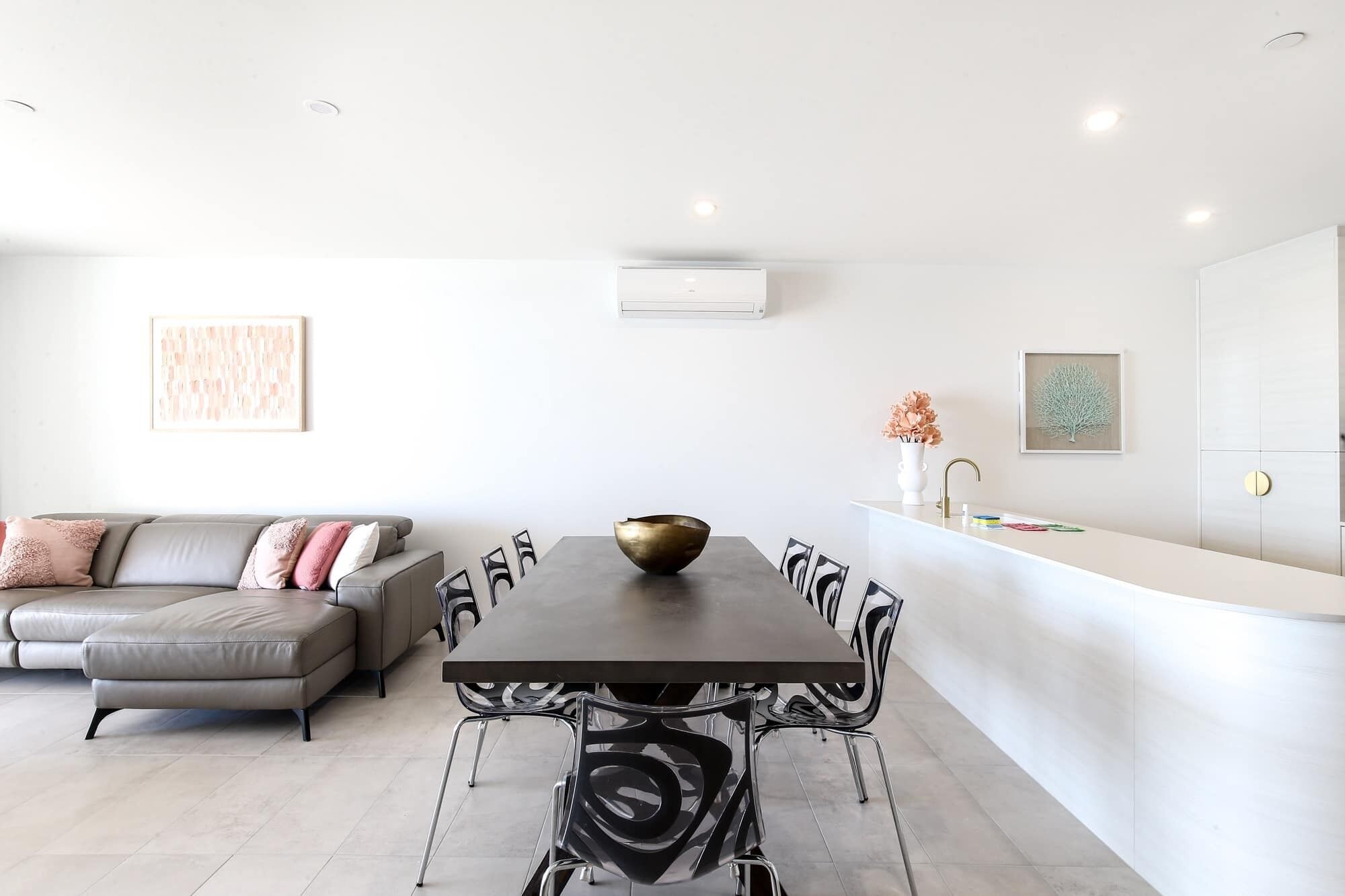 A modern kitchen with a dining table, chairs, and a central decorative bowl.