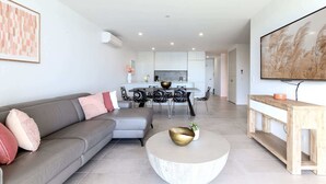 A modern living room with a grey sofa, a round coffee table, and a TV on the wall.
