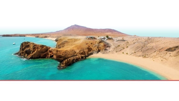 Un paysage c ôtier avec une montagne en arrière-plan, une plage de sable et des falaises rocheuses.