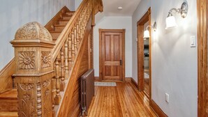 A wooden staircase with intricate carvings, a wooden door, and wall sconces. - Front Royal Retreat ~ 1 Mi to National Park! (Front Royal)