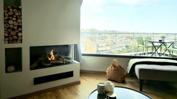 Un salon moderne avec une cheminée, un balcon offrant une vue sur la ville et un coin salon confortable.