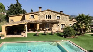 Ein zweistöckiges Steinhaus mit einem Pool im Vordergrund.