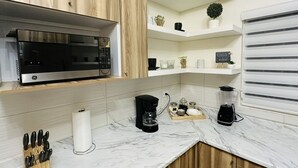A modern kitchen with a built-in microwave, coffee maker, and a knife block. - Privado, Zona segura y cercana a Puentes Internacionales y Consulado.  (Ciudad Ju árez)