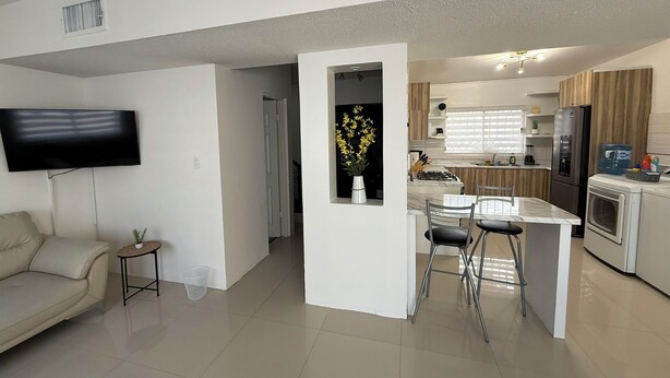 A modern living room with a flat-screen TV, a sofa, and a small side table. - Privado, Zona segura y cercana a Puentes Internacionales y Consulado.  (Ciudad Juárez)