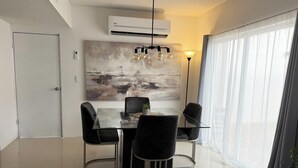 A modern dining area with a glass table, black chairs, a large abstract painting, and a view of the city through large windows. - Privado, Zona segura y cercana a Puentes Internacionales y Consulado.  (Ciudad Juárez)