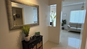A hallway with a large mirror, a console table with baskets, and a potted plant. - Privado, Zona segura y cercana a Puentes Internacionales y Consulado.  (Ciudad Juárez)