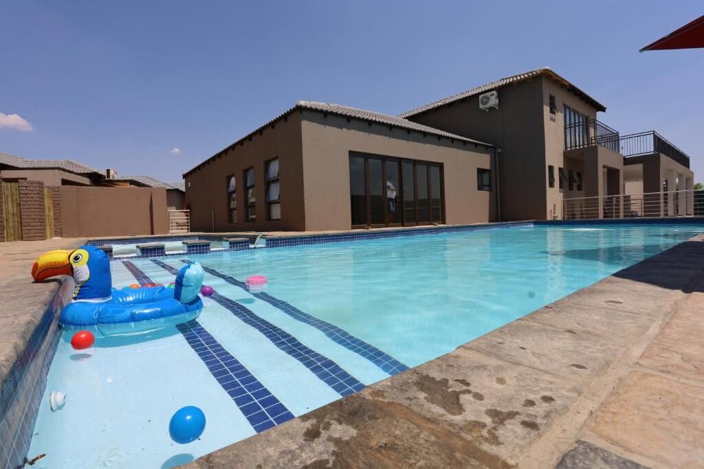 Una piscina con bordo piastrellato blu e bianco, circondata da un solarium in pietra.