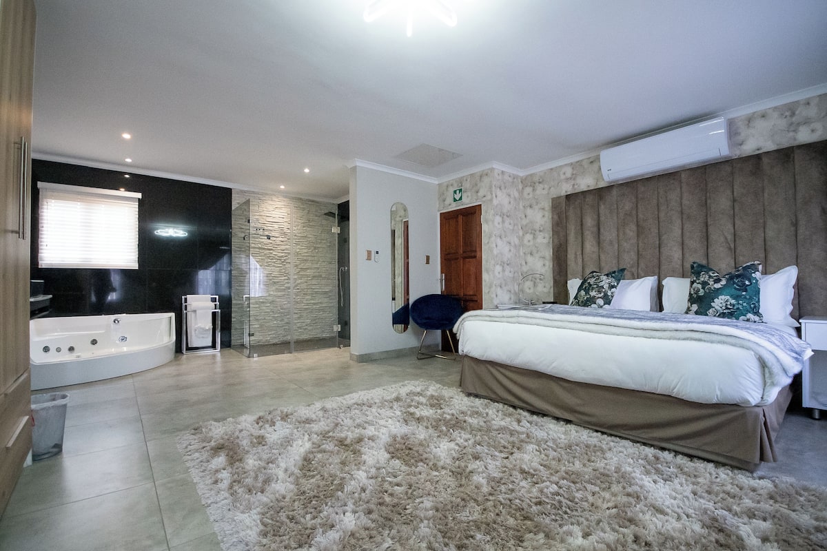 Una camera da letto con un letto grande, un bagno con una vasca e un muro in pietra.
