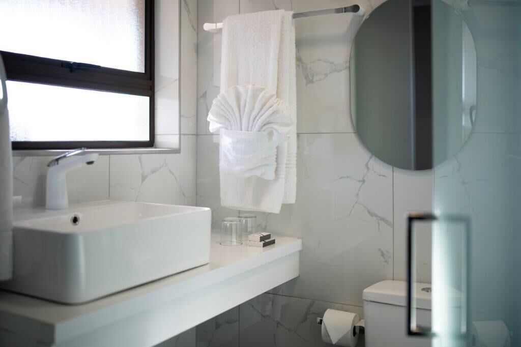 A modern bathroom with a white sink, a towel rack, and a toilet.