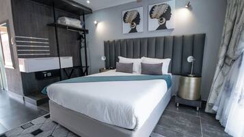 A modern bedroom with a large bed, built-in wardrobe, bedside lamps, and artwork on the wall.