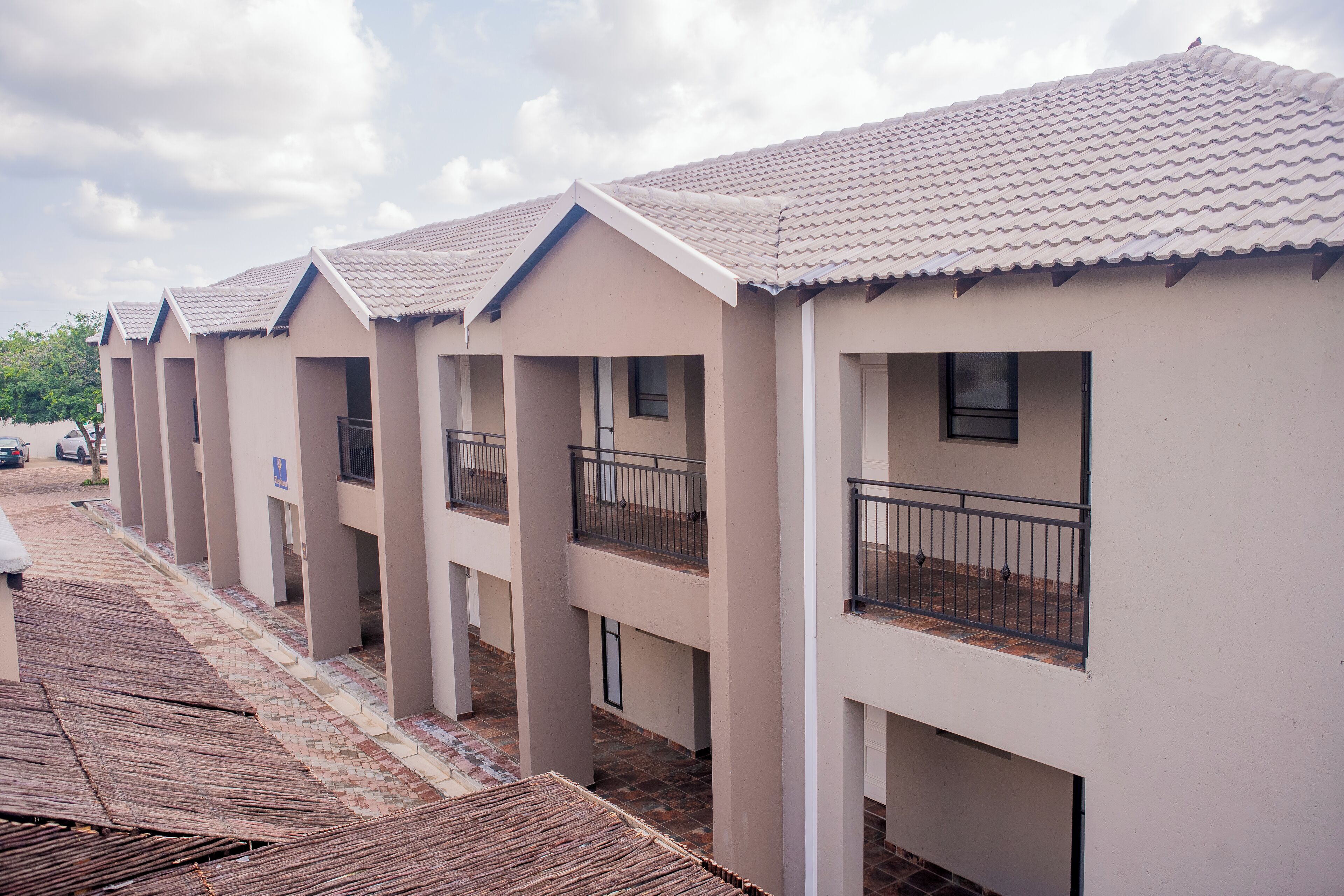 A row of modern, single-story buildings with balconies and a tiled roof.