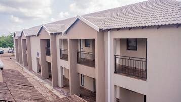 A row of modern, single-story buildings with balconies and a tiled roof.