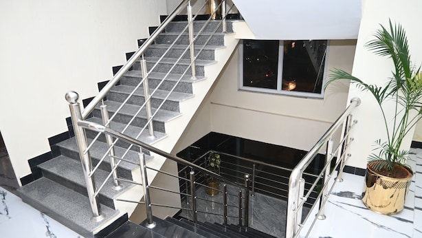 A multi-level interior with a staircase, marble flooring, and a potted plant. - Hotel 99 (Rawalpindi)