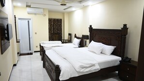 A hotel room with a large bed, a bedside table, a chair, and a television. - Hotel 99 (Rawalpindi)