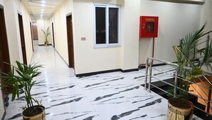 A hotel corridor with a marble floor, potted plants, a fire hose reel, and a staircase. - Hotel 99 (Rawalpindi)