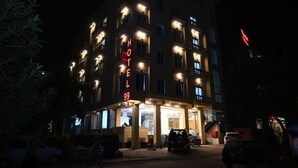 A multi-story hotel with illuminated signage, a ground-level entrance, and a parking area. - Hotel 99 (Rawalpindi)