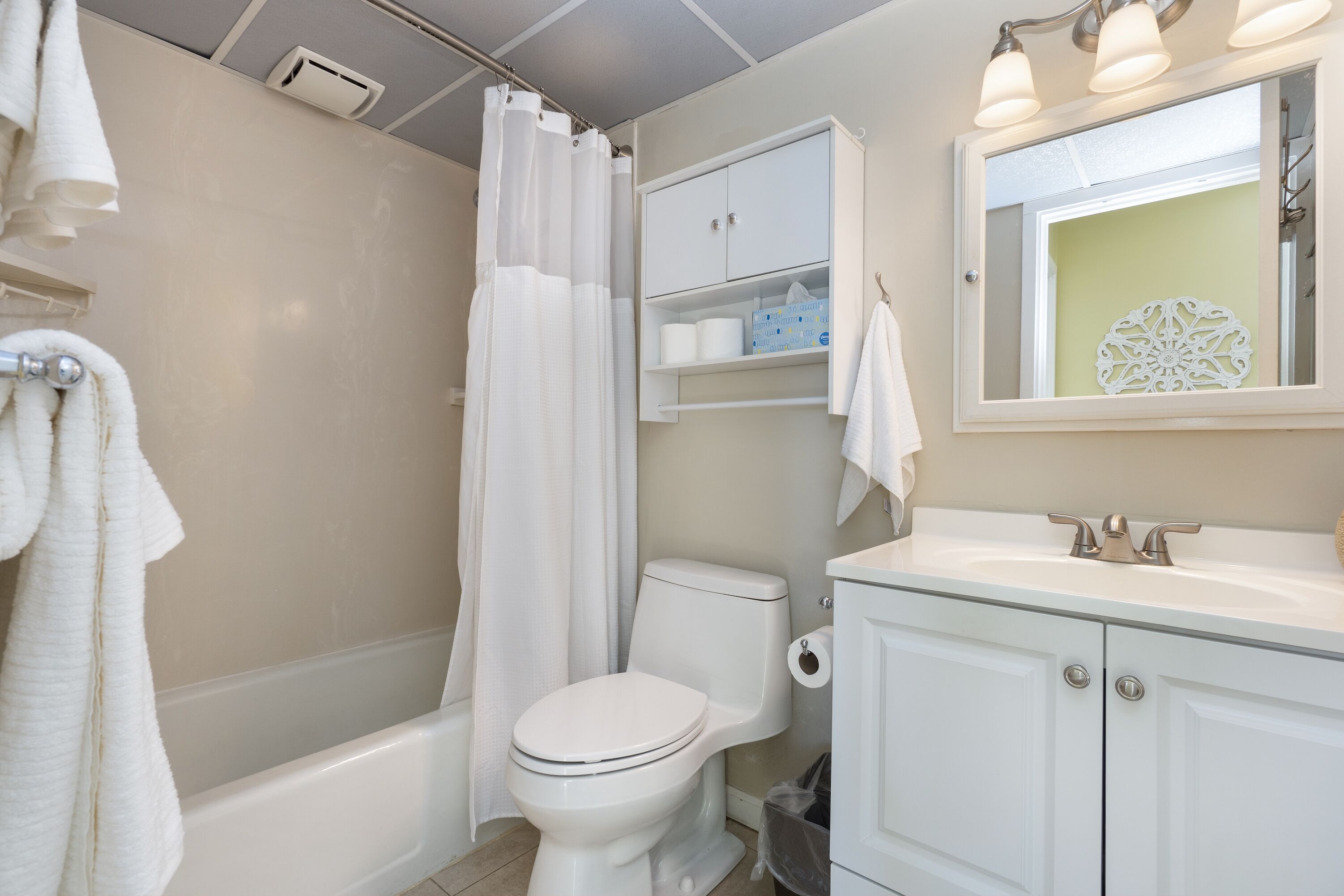 Un baño con bañera, inodoro, lavabo y un espejo sobre el lavabo.