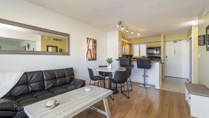 Ein modernes Wohnzimmer mit einem schwarzen Ledersofa, einem Holztisch und einem Essbereich mit rundem Tisch und Stühlen.