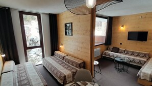 Una habitación con paredes de madera, un conjunto de sofás, una mesa de comedor y un televisor montado en la pared.