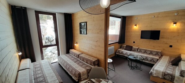 Et værelse med trævægge, en sofa, et spisebord og et fjernsyn hængt på væggen.