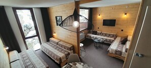 Et lille værelse med to senge, et lille bord og en sofa.