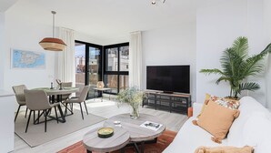 Una sala de estar moderna con sofá, mesa de centro, comedor y televisor.