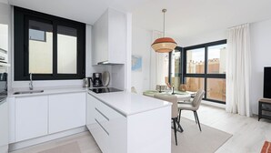 Una cocina moderna con un ventanal grande, un comedor con mesa y sillas, y un televisor.